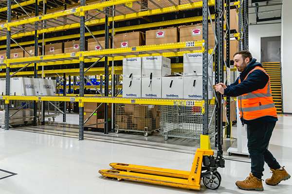 A person pushing a pallet loader in a warehouse facility